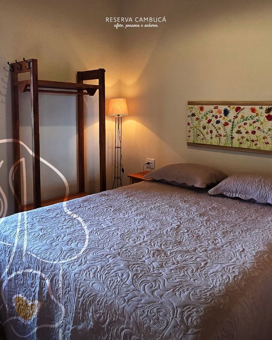 Quarto do Chalé 1 com cama queen, roupeiro de madeira e luminária