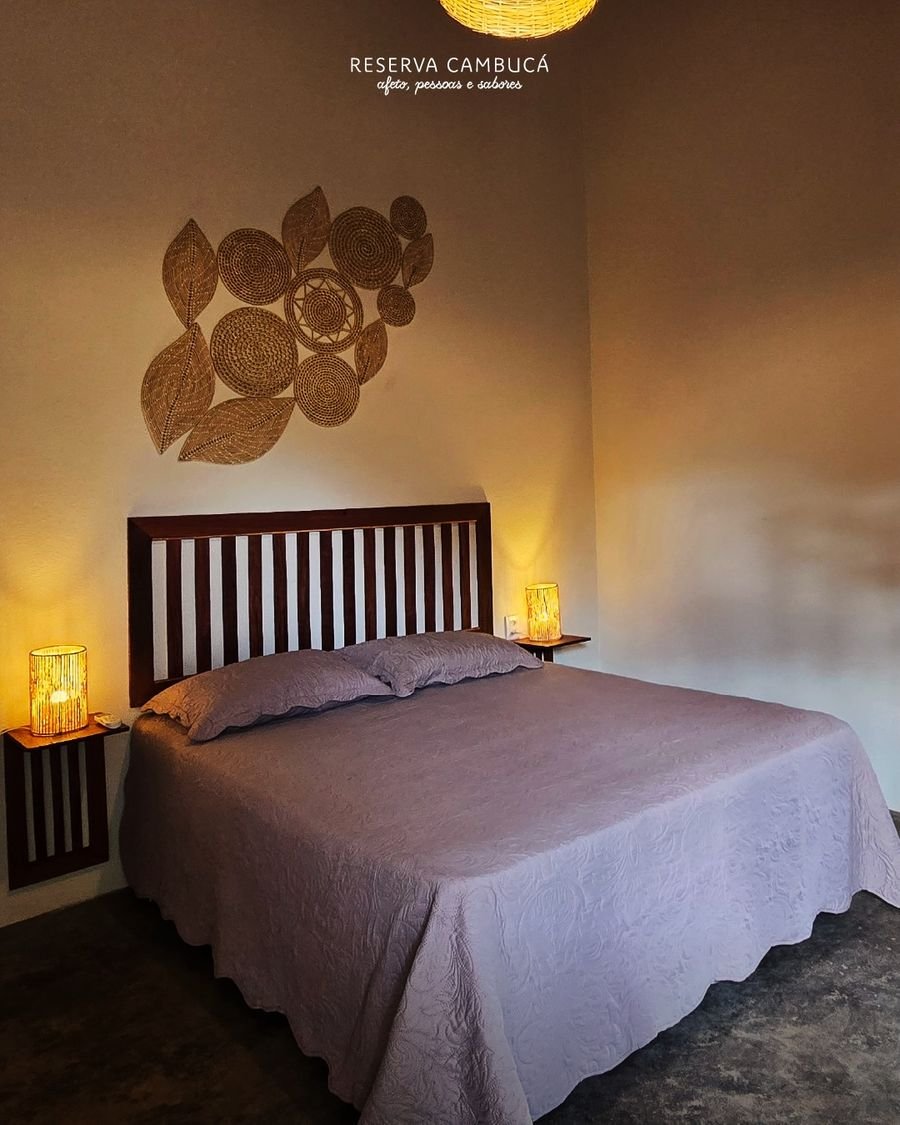 Quarto do Chalé 2 com cama queen, cabeceira de madeira e luminárias de palha