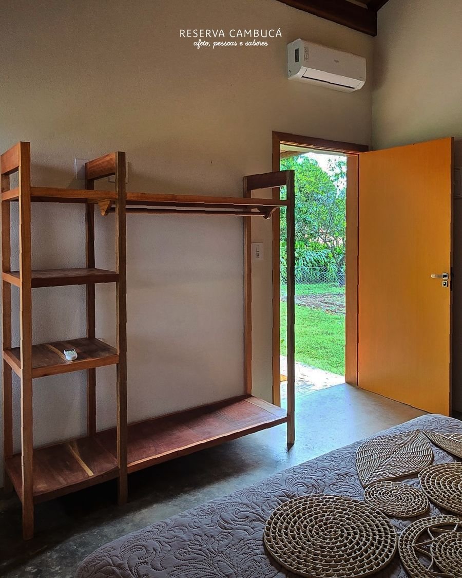 Roupeiro aberto de madeira no Chalé 2, com porta de saída para o jardim