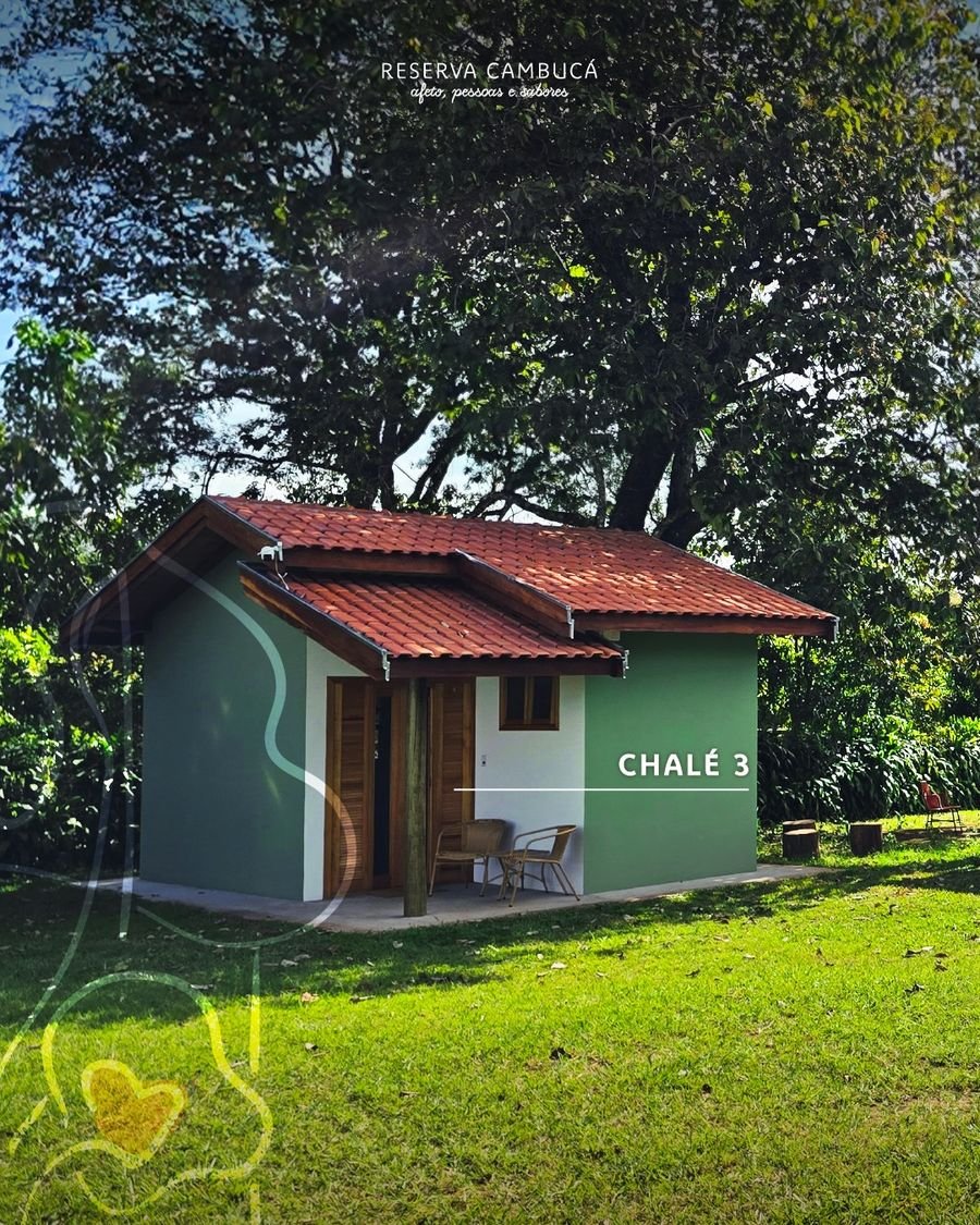 Chalé 3 da Pousada Reserva Cambucá cercado de árvores e gramado, com telhado de barro