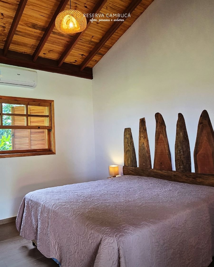 Quarto do Chalé 4 com cama queen, teto de madeira e cabeceira rústica de toras