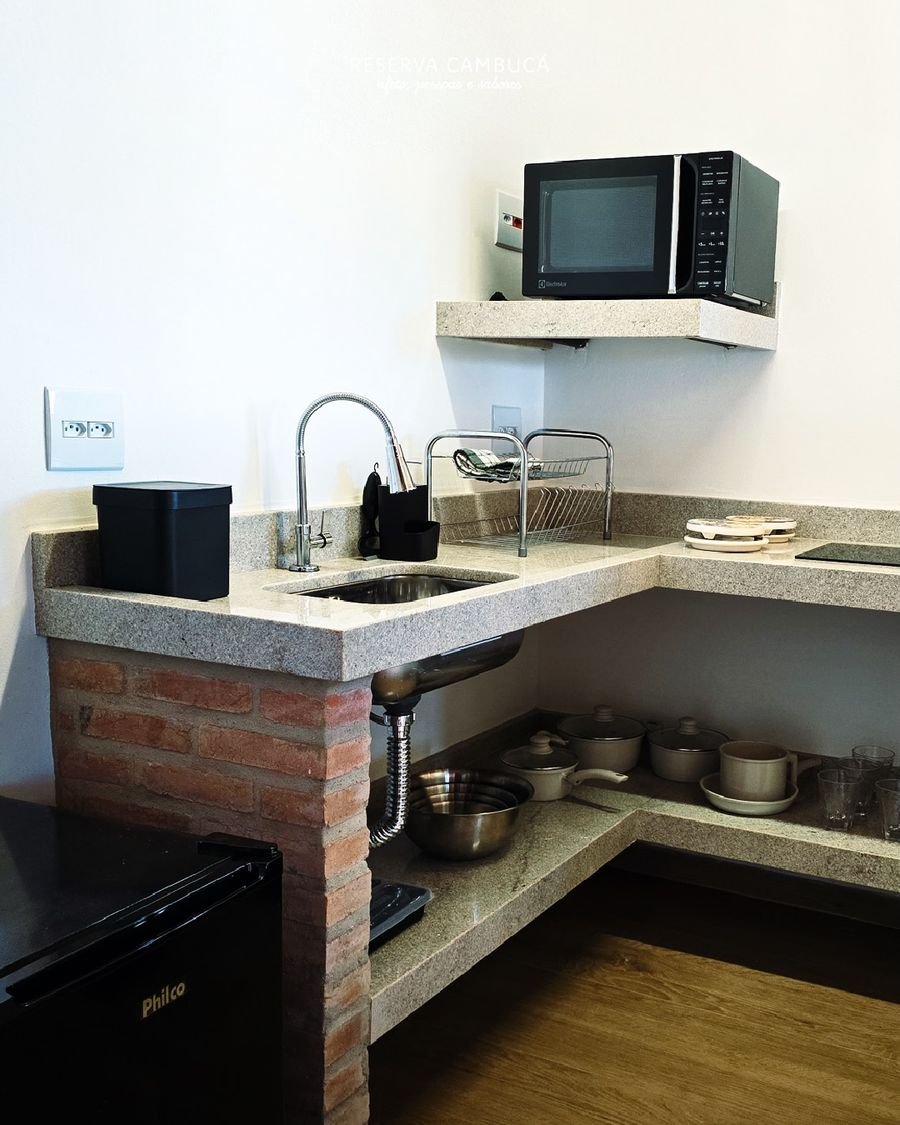 Mini cozinha do Chalé 5 com bancada de granito, pia, micro-ondas e utensílios