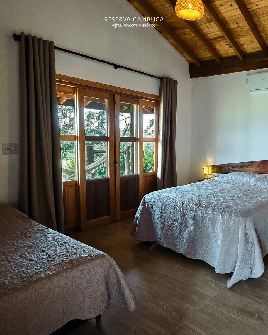 Quarto do Chalé 5 com cama queen, cama de solteiro e portas de madeira para a varanda