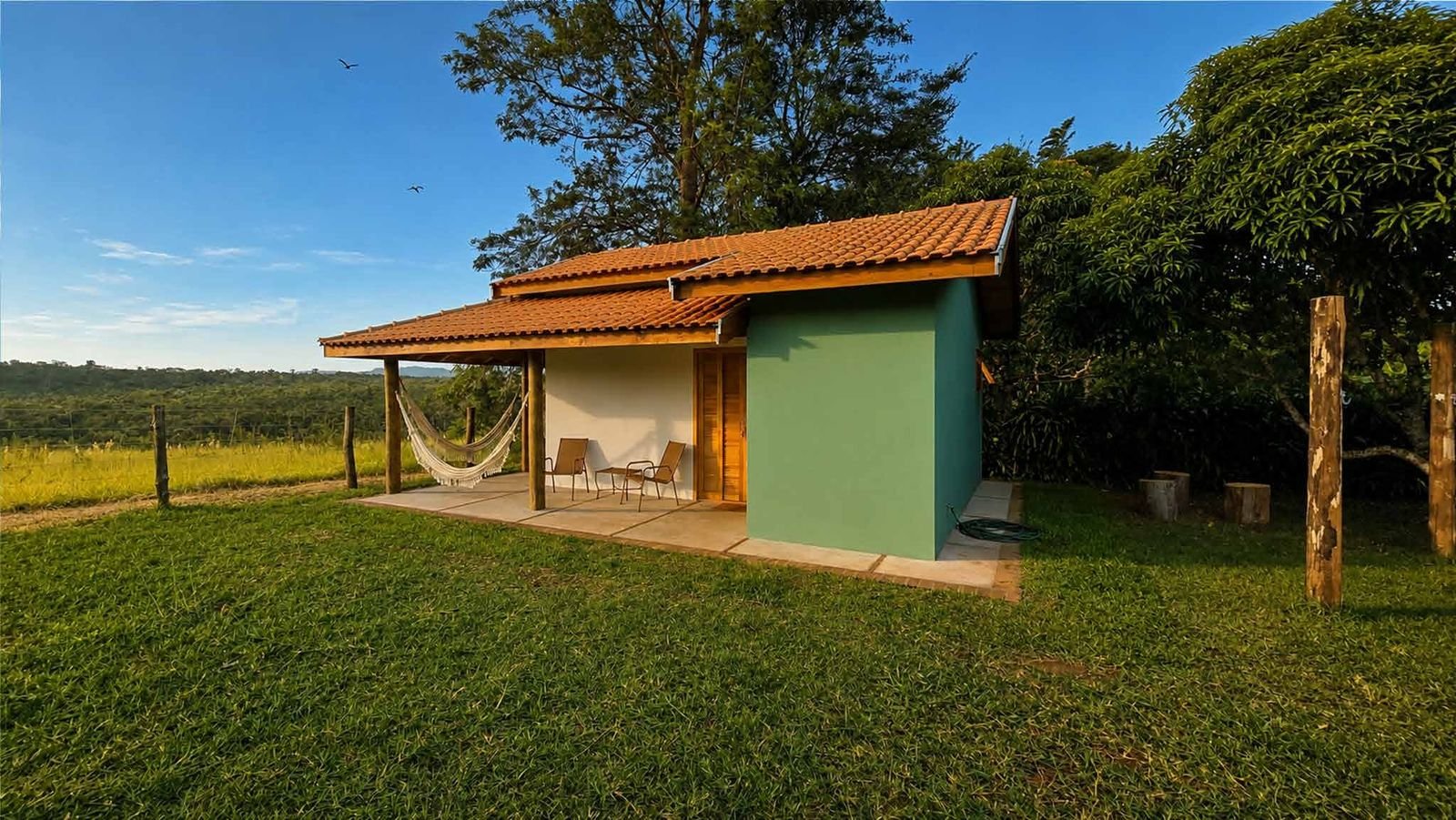 Chalé verde da Pousada Reserva Cambucá com varanda, rede e vista para o campo