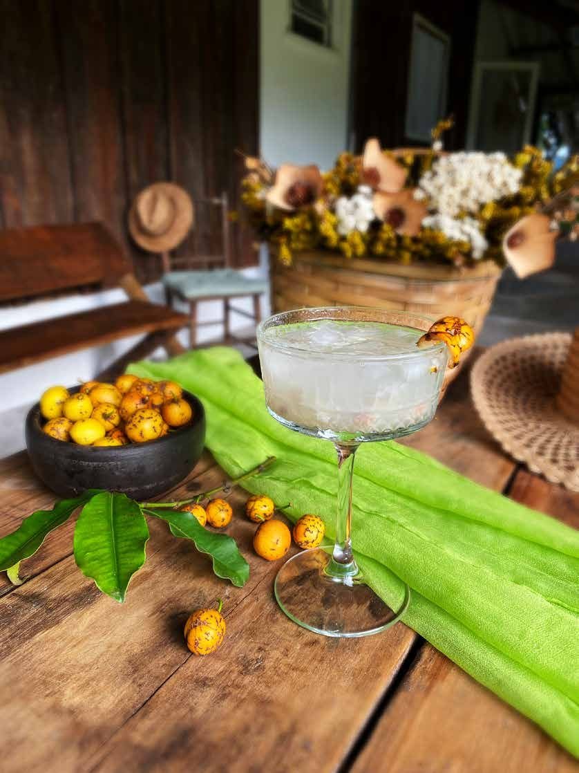Drink servido em taça com frutas amarelas sobre mesa de madeira rústica