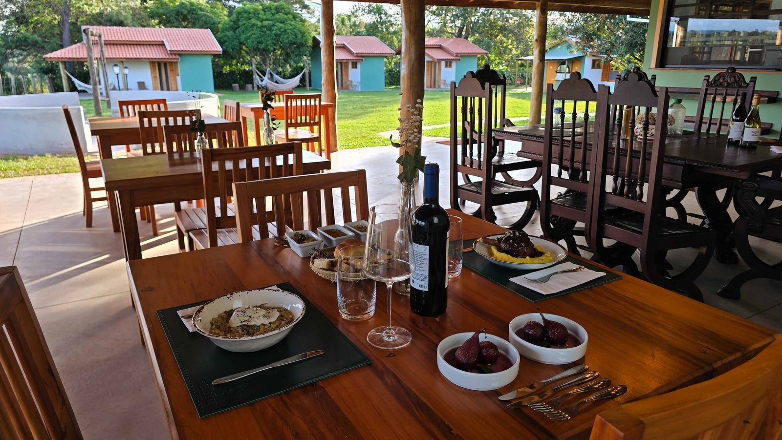 Salão do restaurante da Pousada Reserva Cambucá, com mesas de madeira e janelas para a paisagem