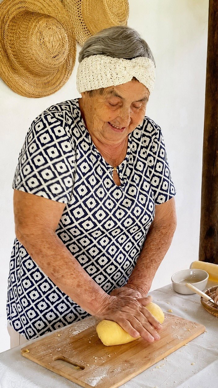 Teia sovando massa fresca sobre a tábua de madeira na cozinha da Pousada Reserva Cambucá