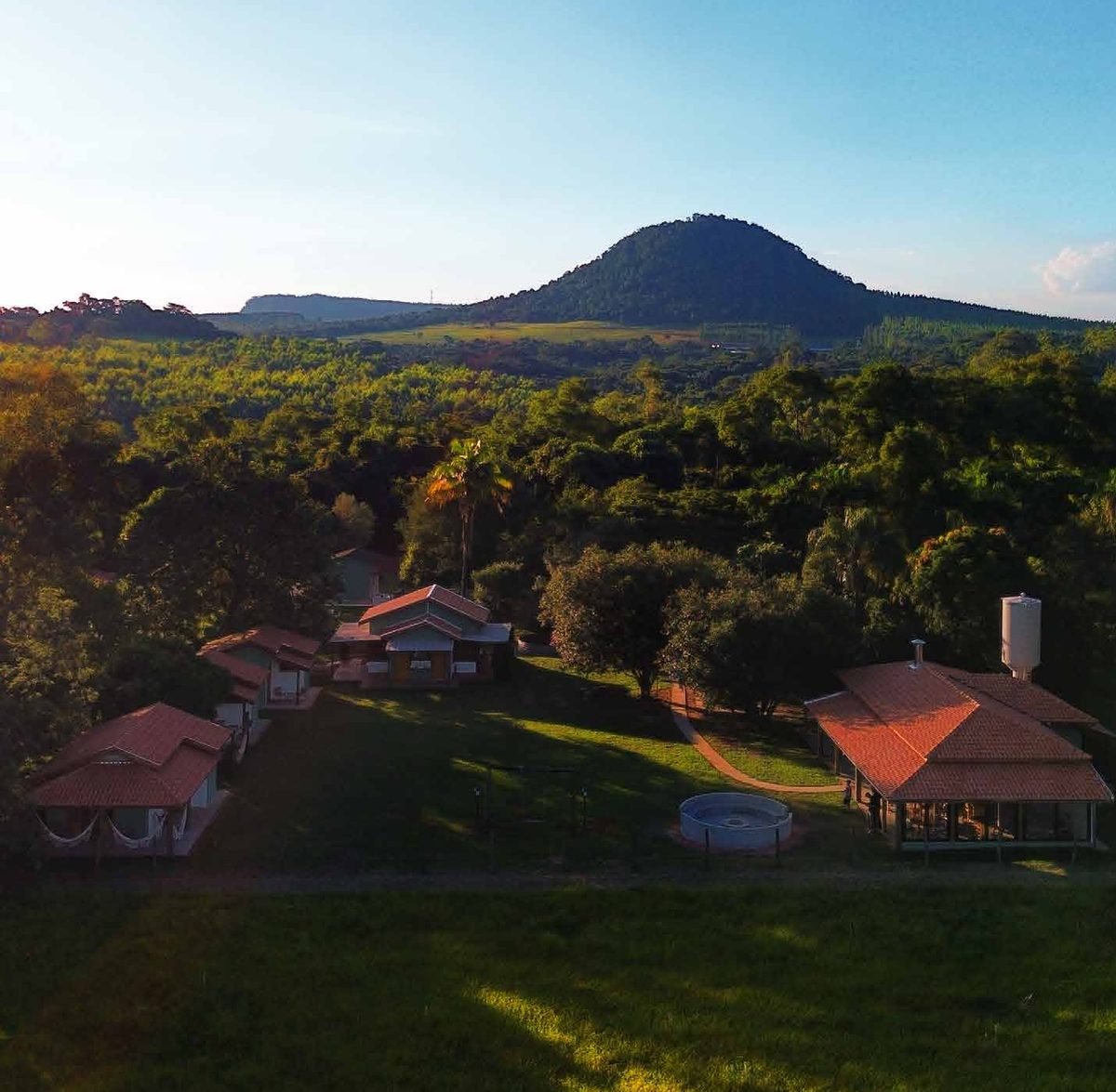 Vista aérea da Pousada Reserva Cambucá, com os chalés, o restaurante e a serra ao fundo